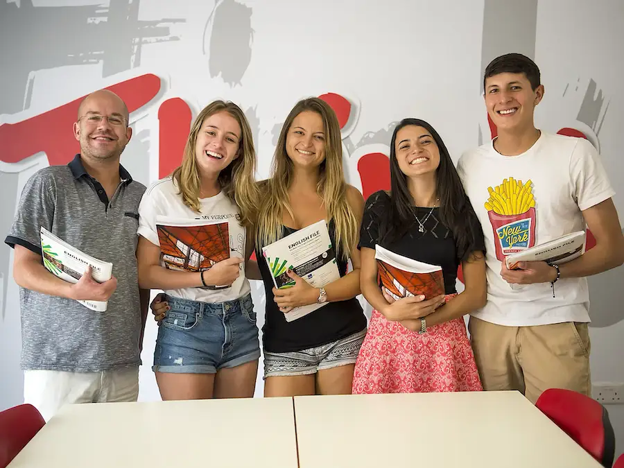 Three women and two men with an English textbook