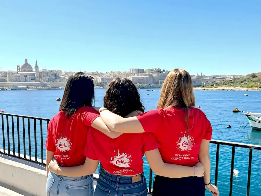 Three women from behind in front of the sea with a red t-shirt