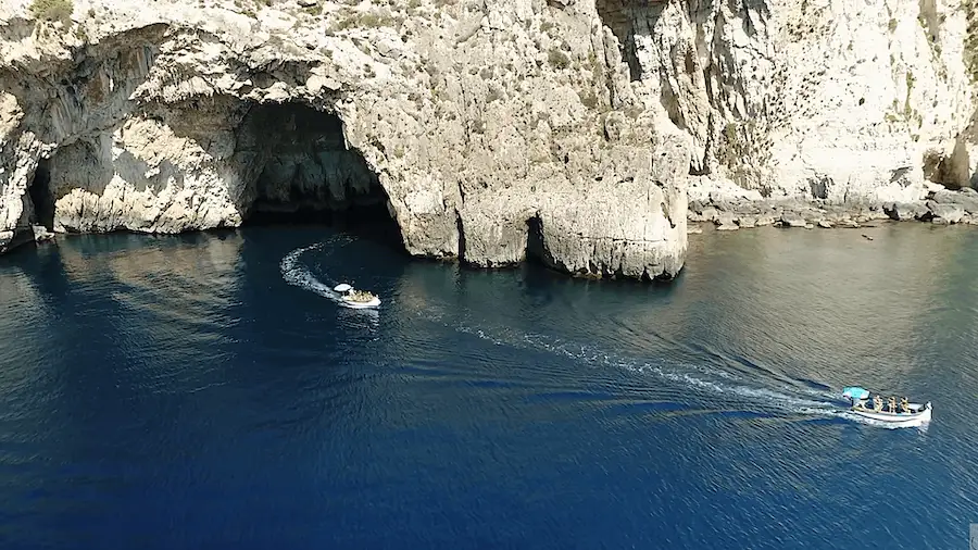 Two boats leaving the large arch of the Blue Grotto of Malta