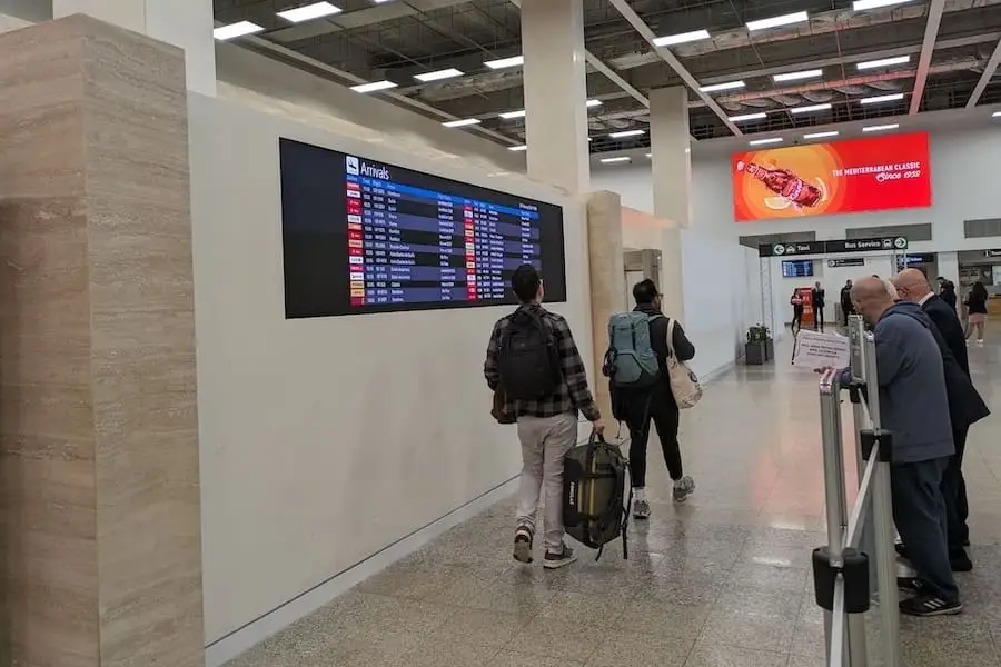 Deux voyageurs vus de dos à la sortie de l'aéroport de Malte